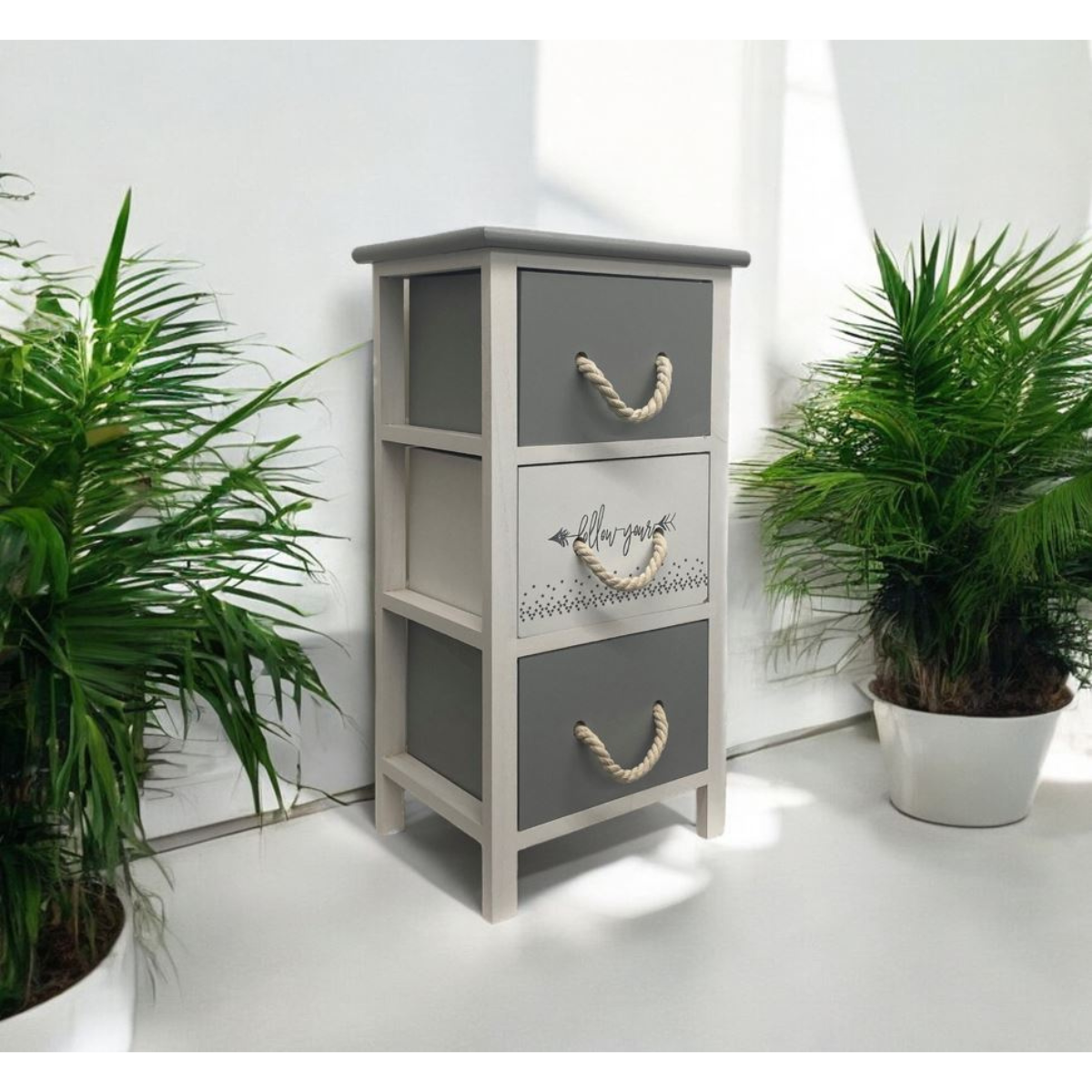 Kommode RopeCharm in Grau-Weiss mit Seilgriffen, dekorativ inszeniert zwischen grünen Zimmerpflanzen.